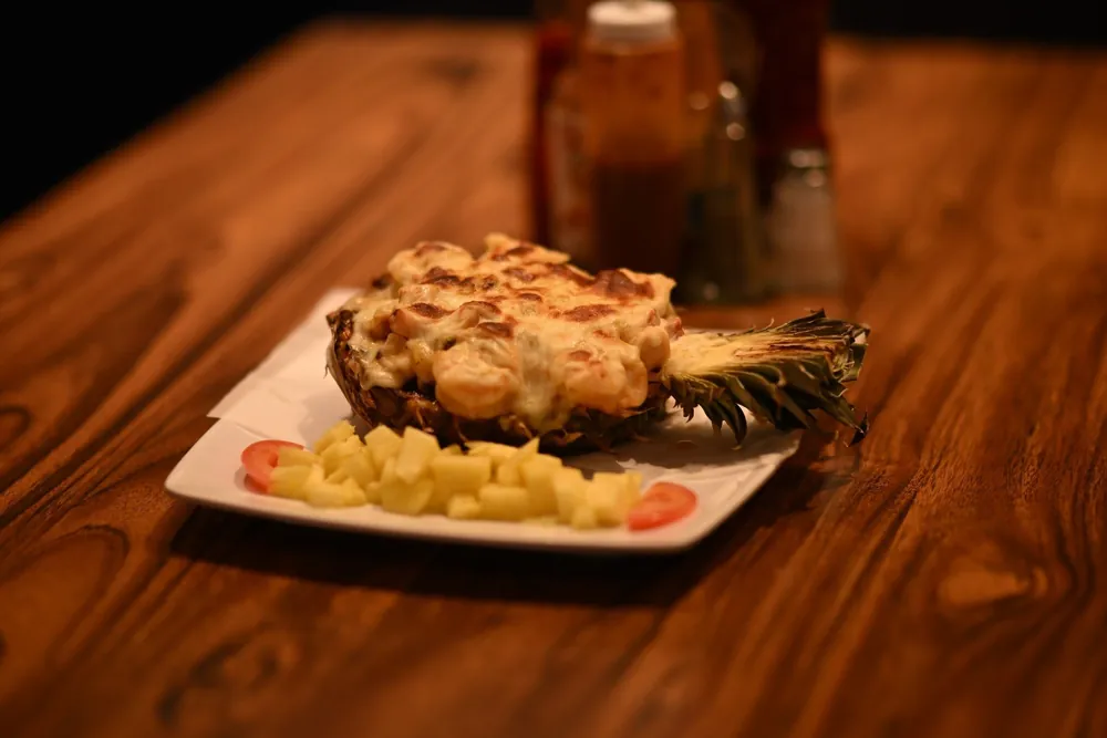 Piña Rellena — shrimp in a cheesy sauce, baked in half a pineapple, with fresh pineapple on the side