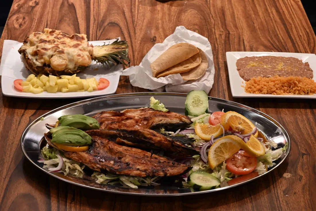 Pescado a la talla — grilled fish with avocado, citrus and salad, with piña rellena, tortillas, rice and beans